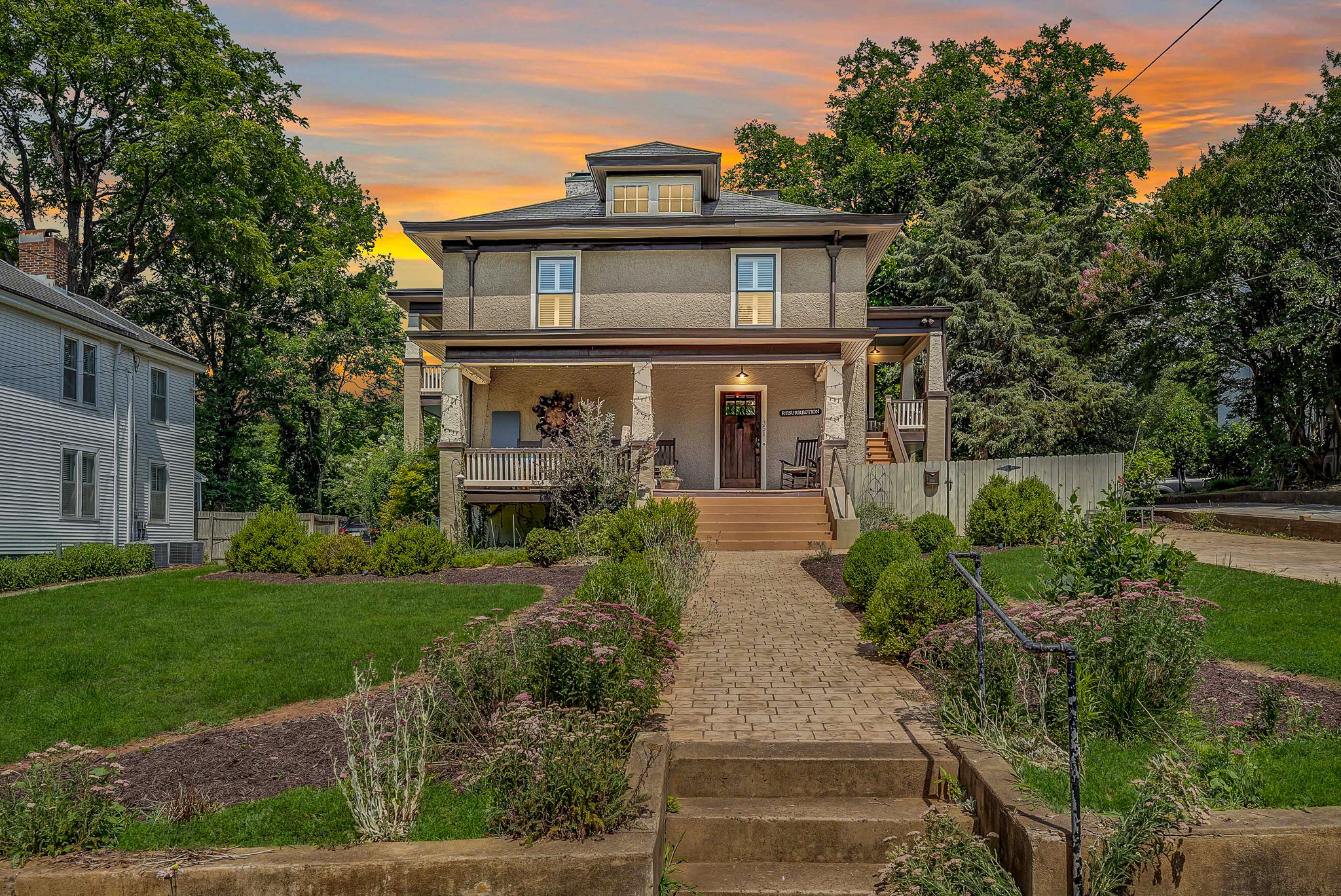 Two‑story beige house with a wide front porch, landscaped front yard, and a stone path leading up to the entrance at sunset belonging to Sponsored Residential Providers Jeff and Sarah McLane in Lynchburg, Virginia.