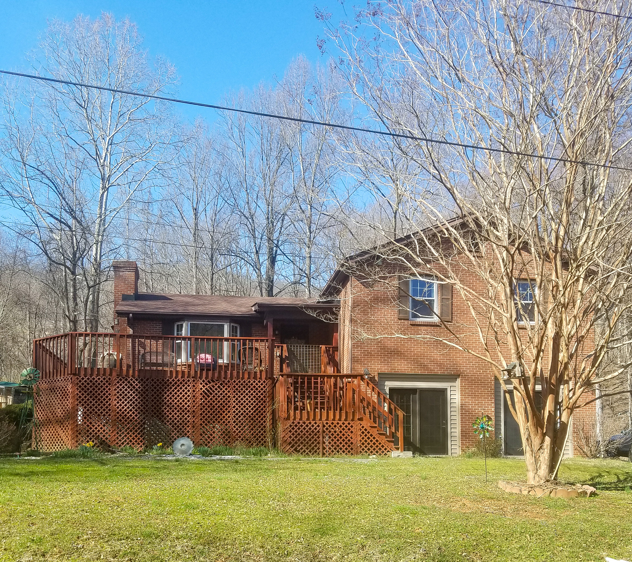 Brick house with an elevated wooden deck, bare winter trees, and a grassy yard belonging to Sponsored Residential Provider Sharon Litchford in Monroe, Virginia.
