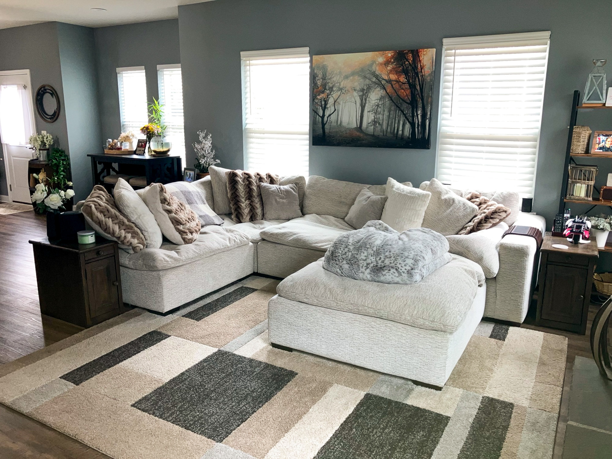 Living room with a large light‑colored sectional sofa, patterned rug, wall art, and windows letting in natural light inside the home of Sponsored Residential Providers Crystal and Christopher Cameron in Fredericksburg, Virginia.
