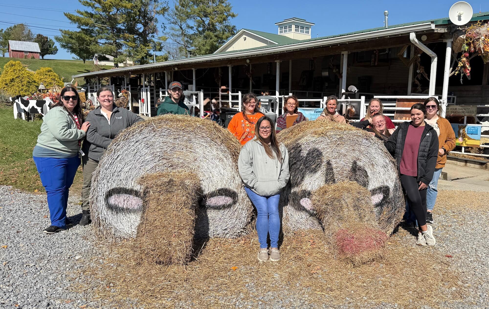 A group of Wall DSPs gathered at a pumpkin patch with hay bales painted to look like cows.