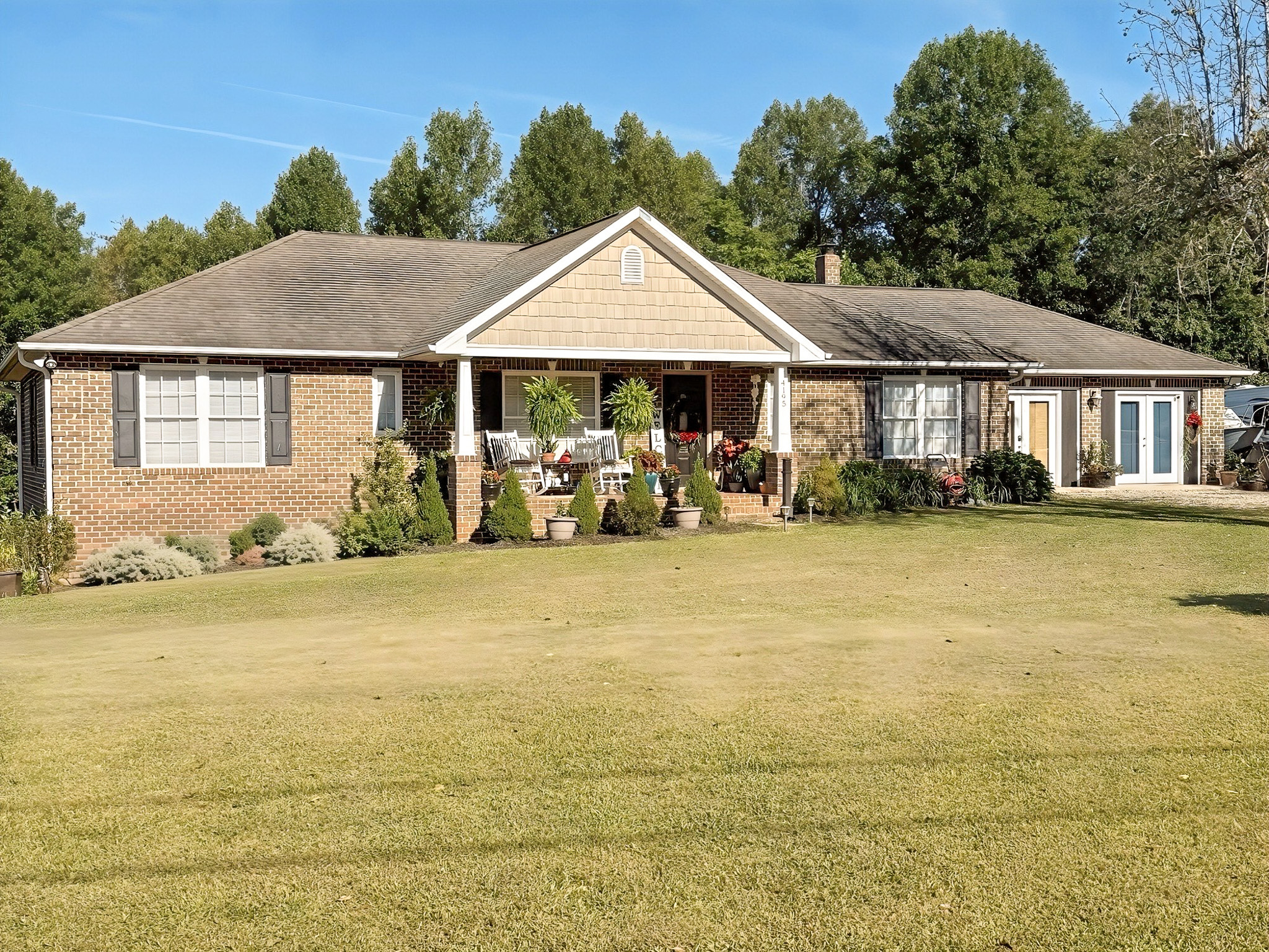 A long brick ranch-style house with a covered front porch, landscaped shrubs, and a wide grassy yard belonging to Group Home Providers Kim and Rick Duncan in Patrick Springs, Virginia.