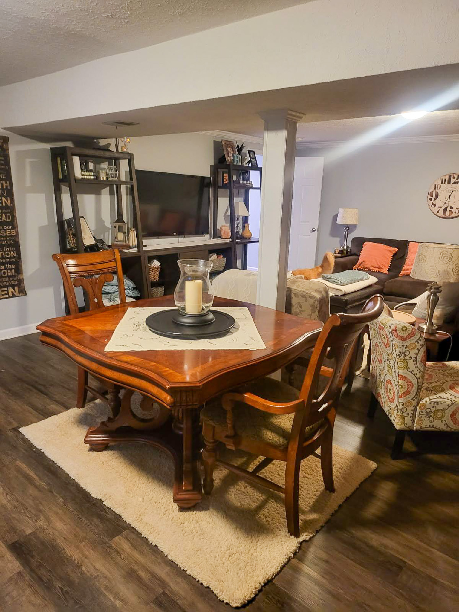A wooden dining table with chairs sits on a small rug beside bookshelves and seating in an open living area inside the home of Sponsored Residential Providers Scott and Tedra Flanders in Lynchburg, Virginia.
