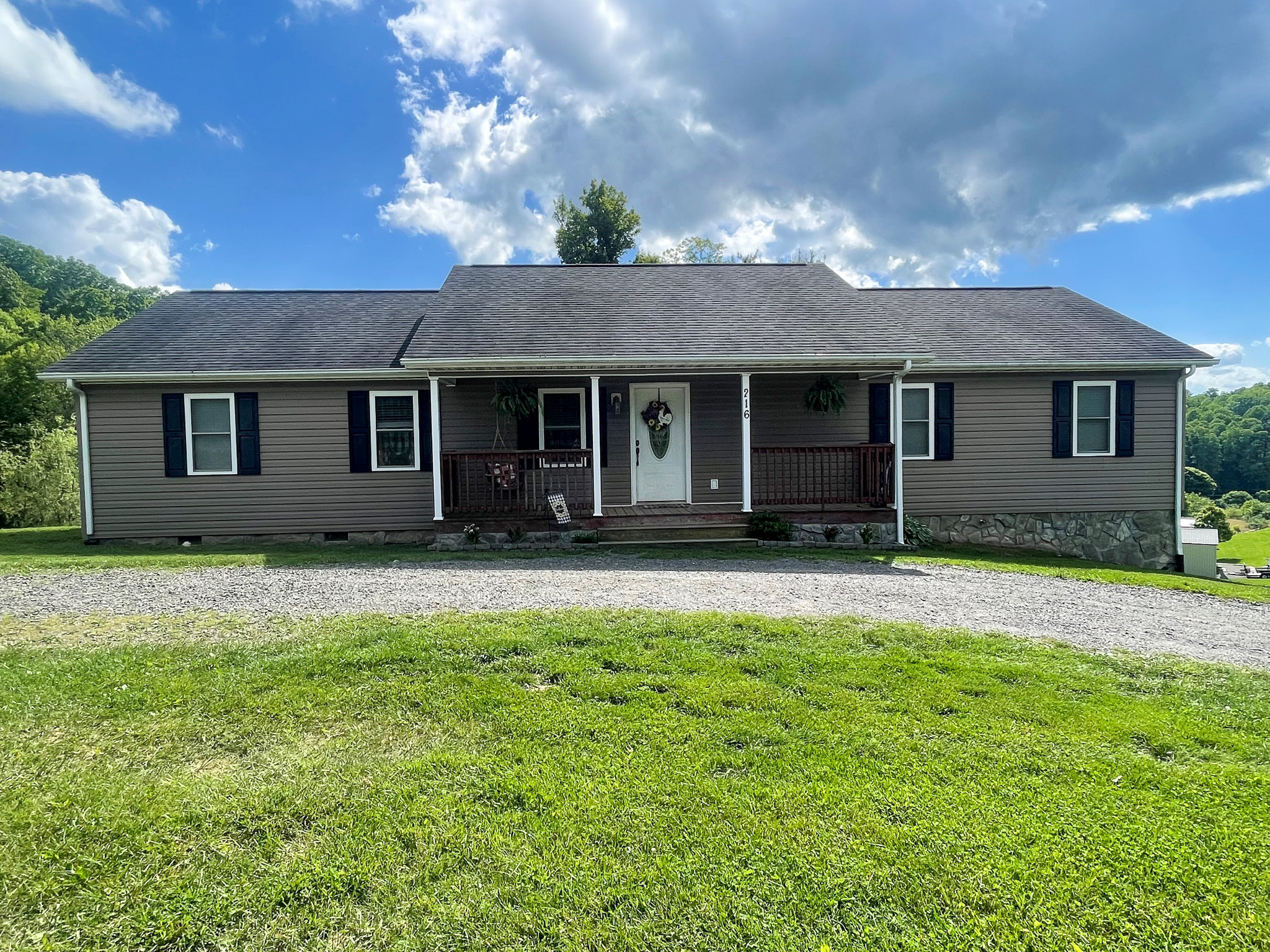 Single‑story house with a small front porch, dark shutters, and a gravel driveway, set against a grassy yard belonging to Sponsored Residential Provider Chancie Haga in Woodlawn, Virginia.