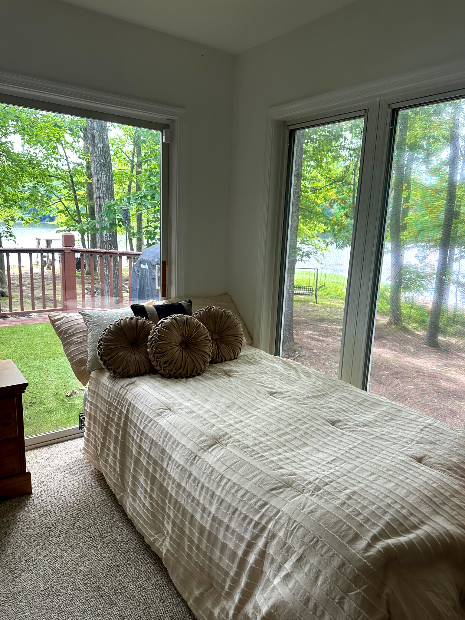 Small bedroom with a single bed beside large windows overlooking a wooded lakeside view inside the home of Group Home Provider Ana Garcia in Spotsylvania, Virginia.