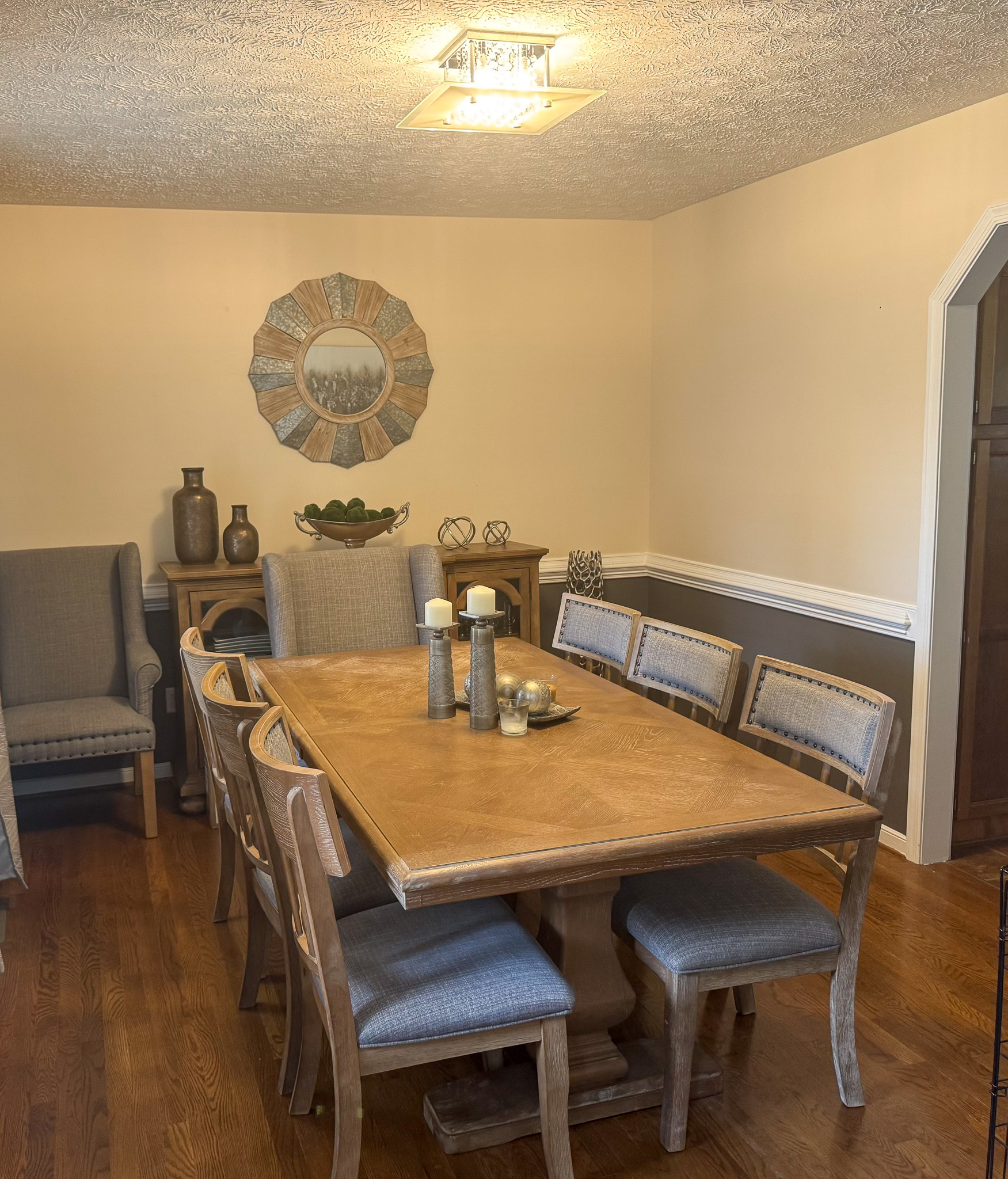 A dining room features a wooden table with upholstered chairs, decorative candles, and accent pieces arranged along the back wall inside the home of Sponsored Residential Provider Durand Holloway in Chester, Virginia.