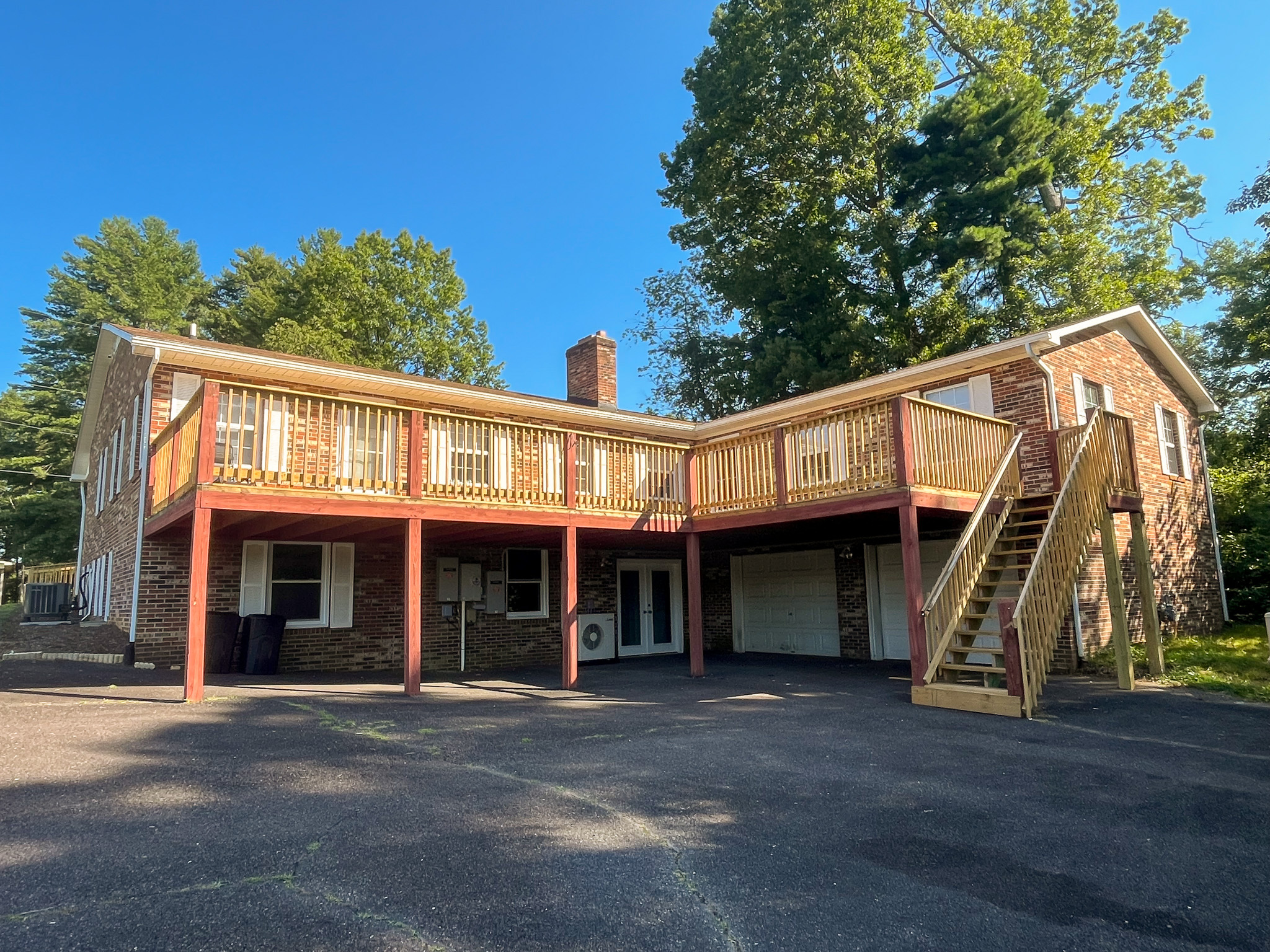 Two‑story brick house with an elevated wooden deck, exterior staircase, and paved driveway beneath it belonging to Sponsored Residential Providers Penny Day and Steven Coleman in Hillsville, Virginia.