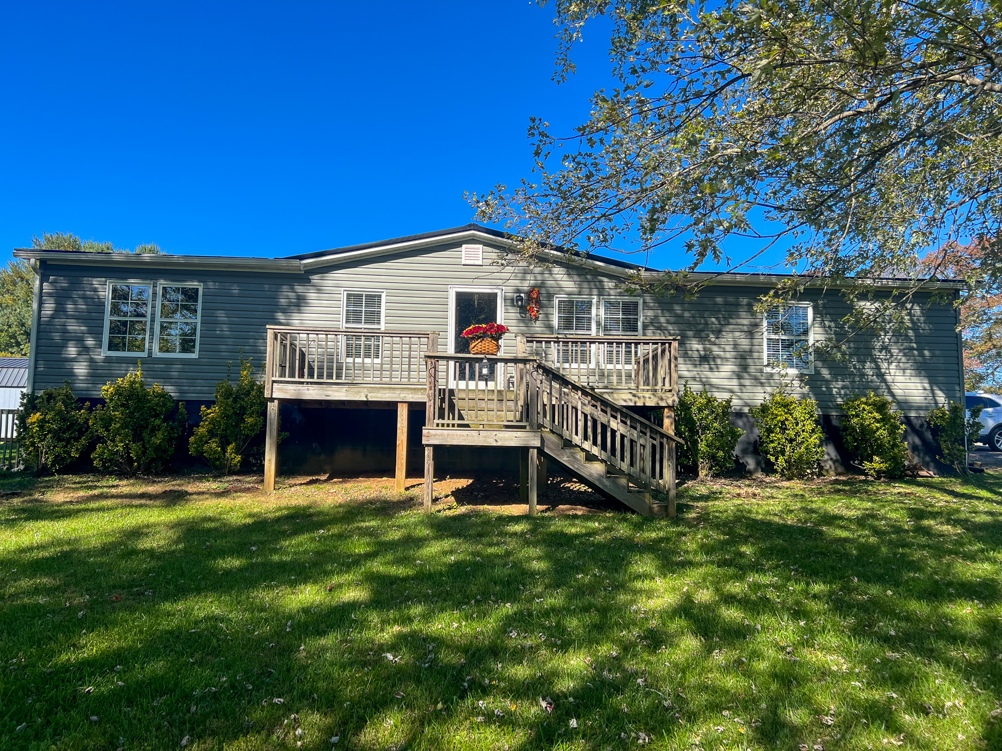 A single‑story home with gray siding, a raised wooden front porch with steps, shrubs along the foundation, and a large grassy yard belonging to Sponsored Residential Provider Christina Bedsaul in Hillsville, Virginia.