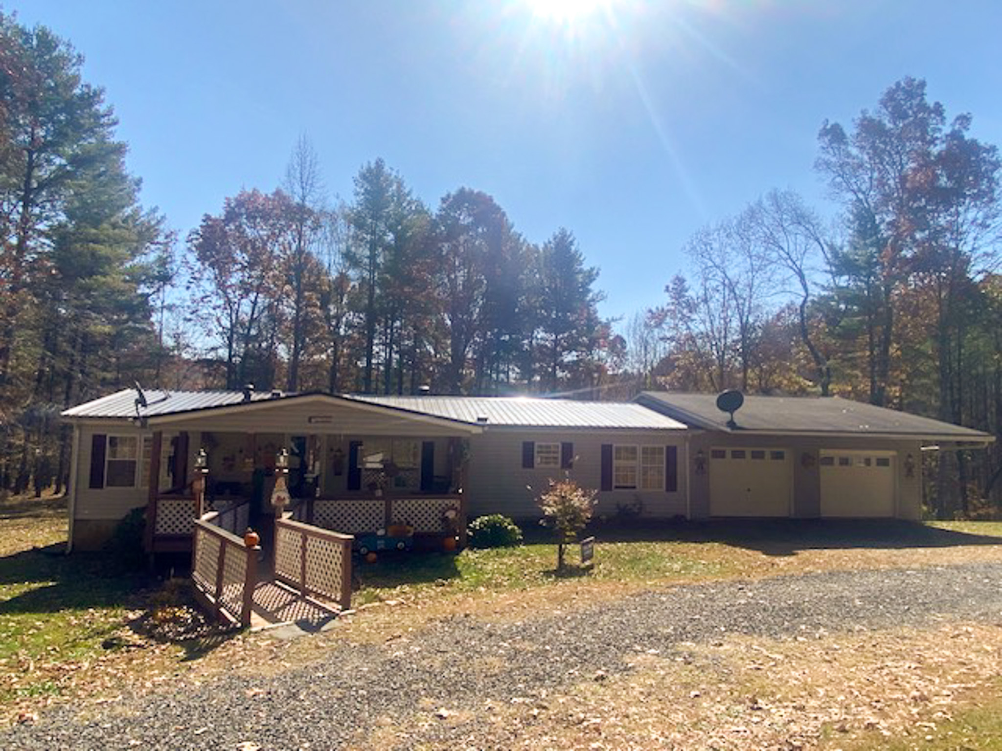 Single‑story house with a covered porch, attached garage, front ramp, and surrounding trees under bright sunlight belonging to Sponsored Residential Provider Angel Dixon in Woodlawn, Virginia.