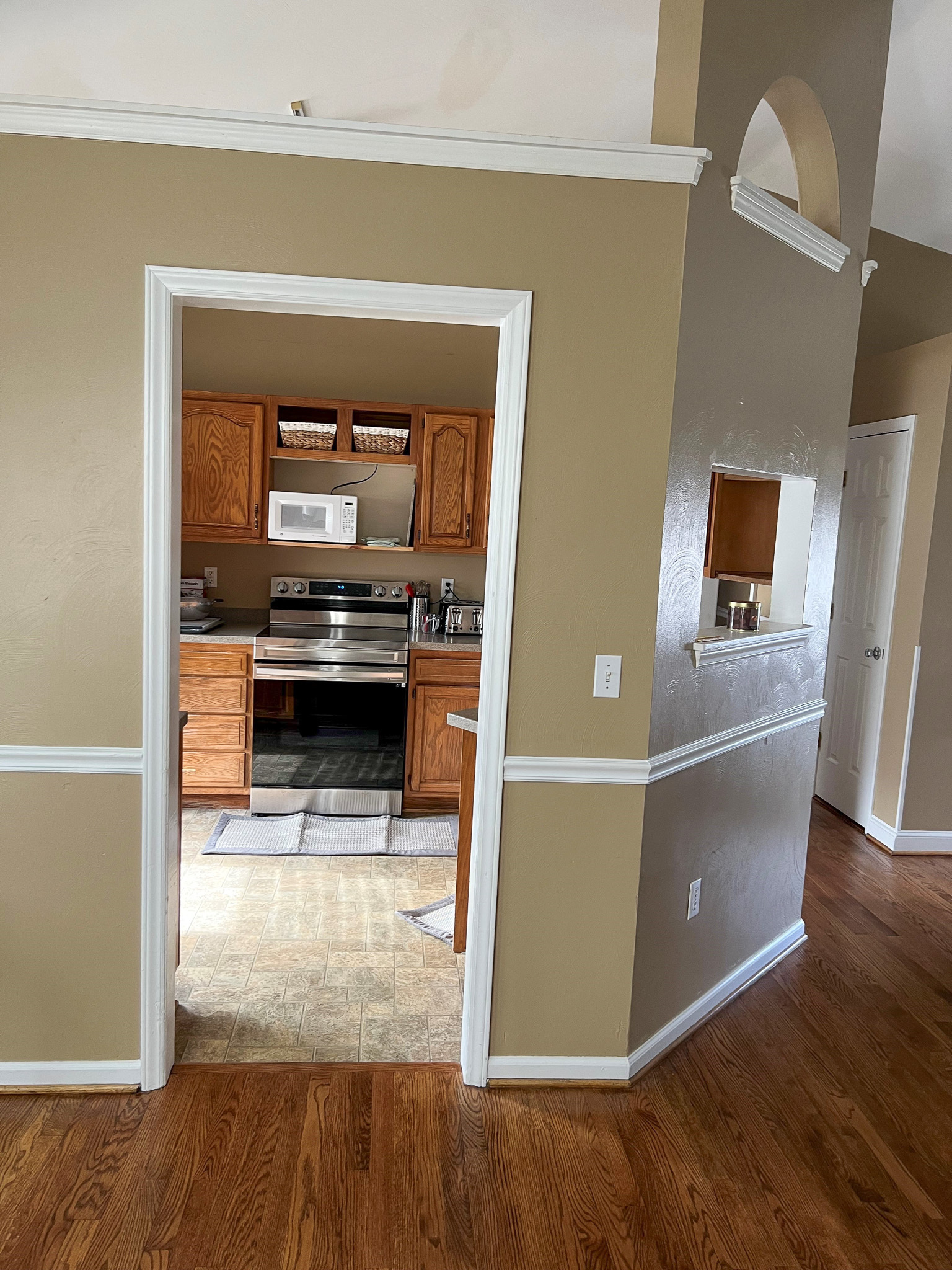 A view into a kitchen with wooden cabinets, stainless steel appliances, and a tiled floor framed by a doorway inside the home of Group Home Providers Anthony and Melissa Johnson in Daleville, Virginia.
