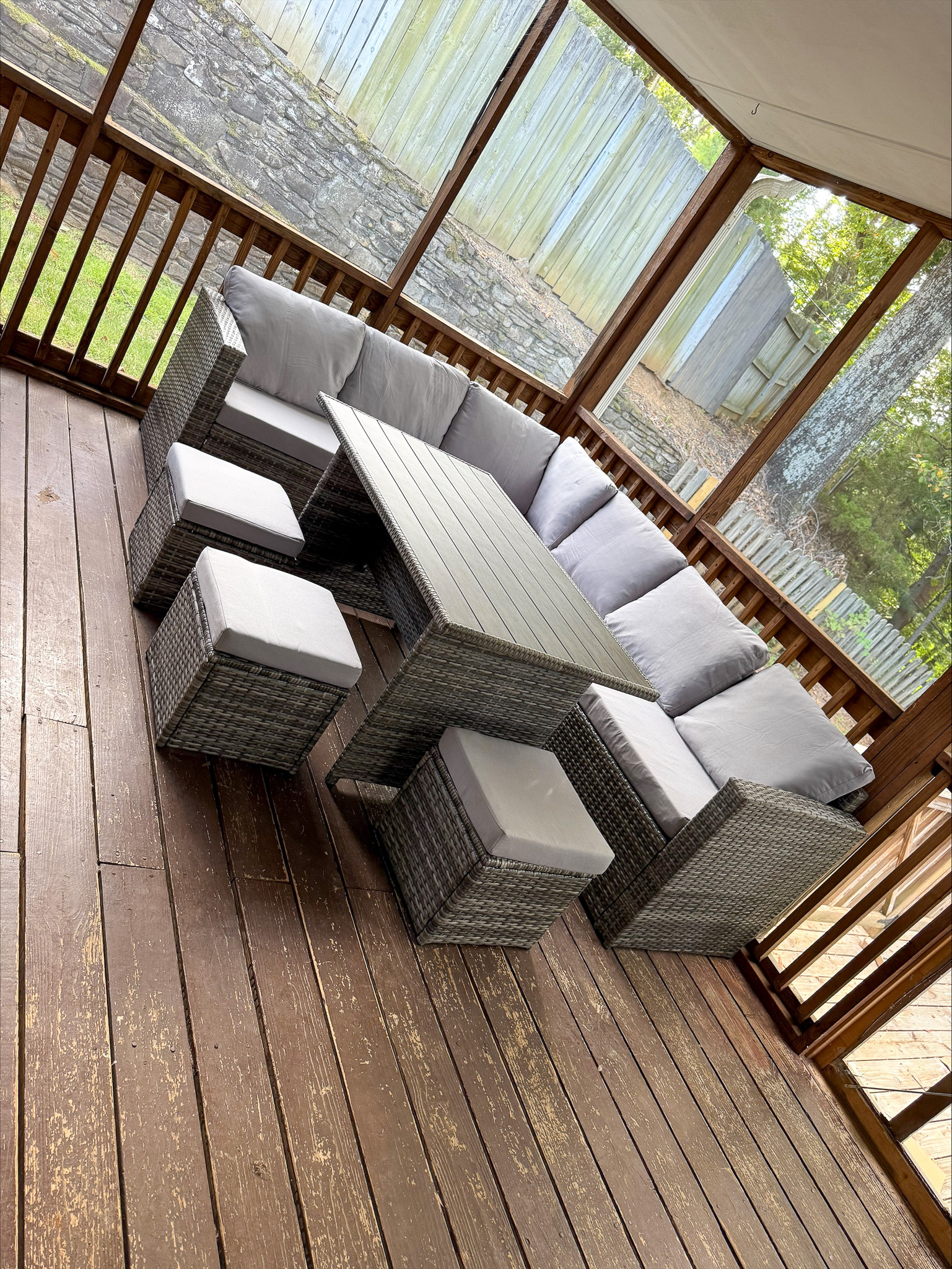 A screened porch with a gray outdoor sectional, matching stools, and a wooden floor inside the home of Group Home Provider Tina Langhorn in Roanoke, Virginia.