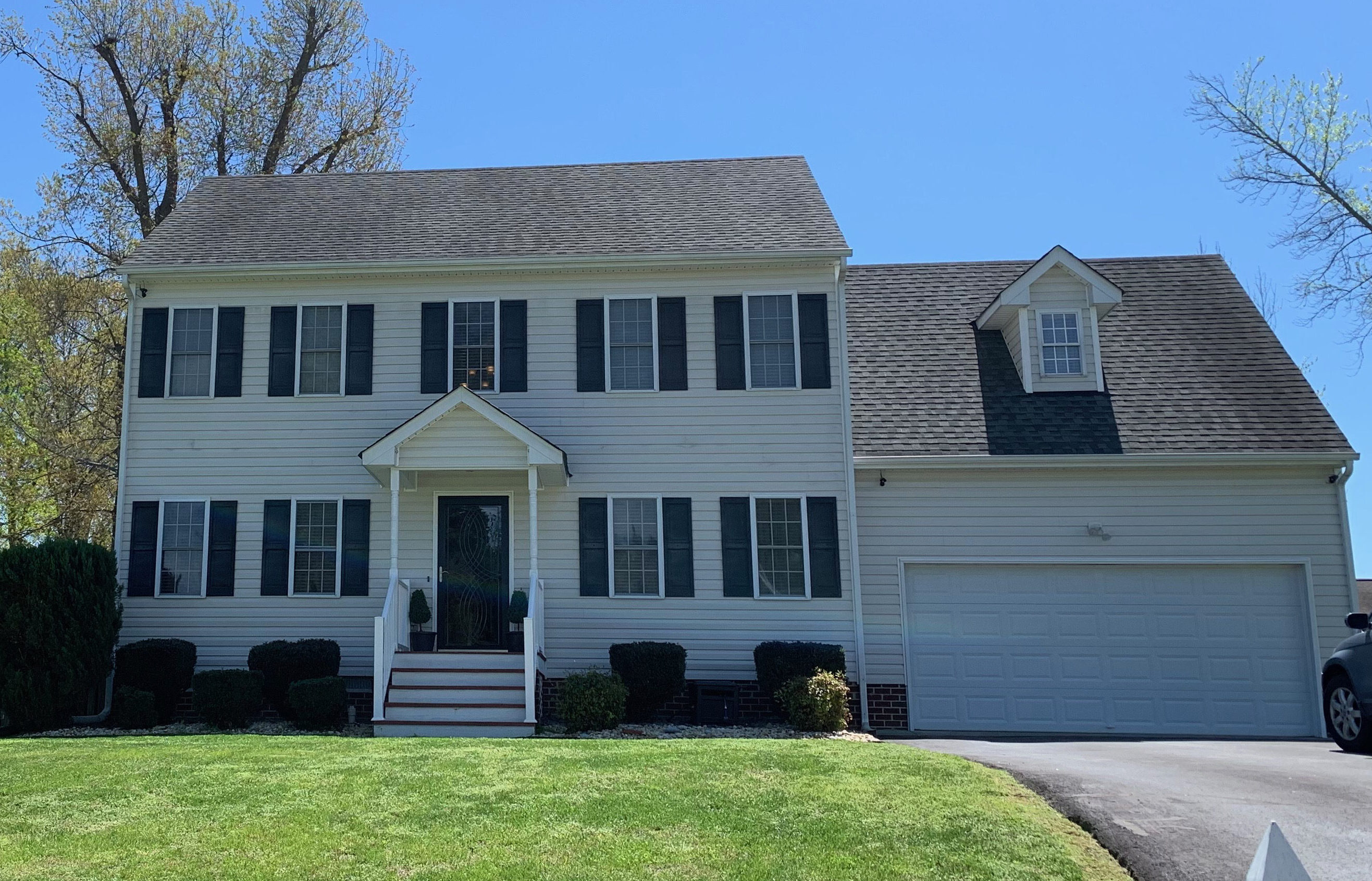 A two‑story light-colored house with dark shutters features a central front entrance, a wide driveway, and a neatly maintained lawn with trimmed shrubs belonging to Sponsored Residential Provider Penny Miller in North Chesterfield, Virginia.