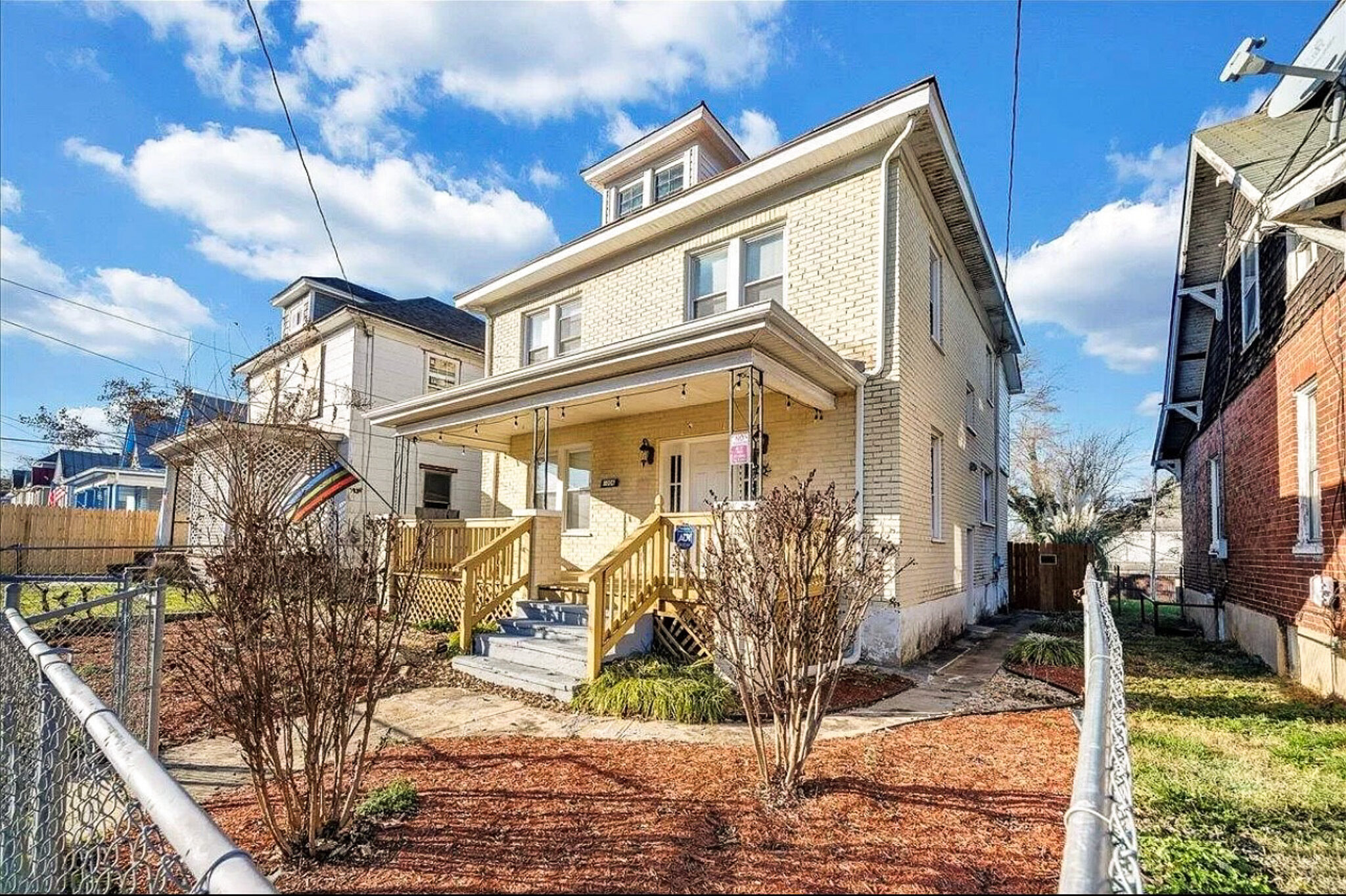 A two‑story house with a covered front porch, new wooden steps, and a fenced yard with small shrubs along the walkway belonging to Sponsored Residential Provider Jessica Peregrino in Roanoke, Virginia.