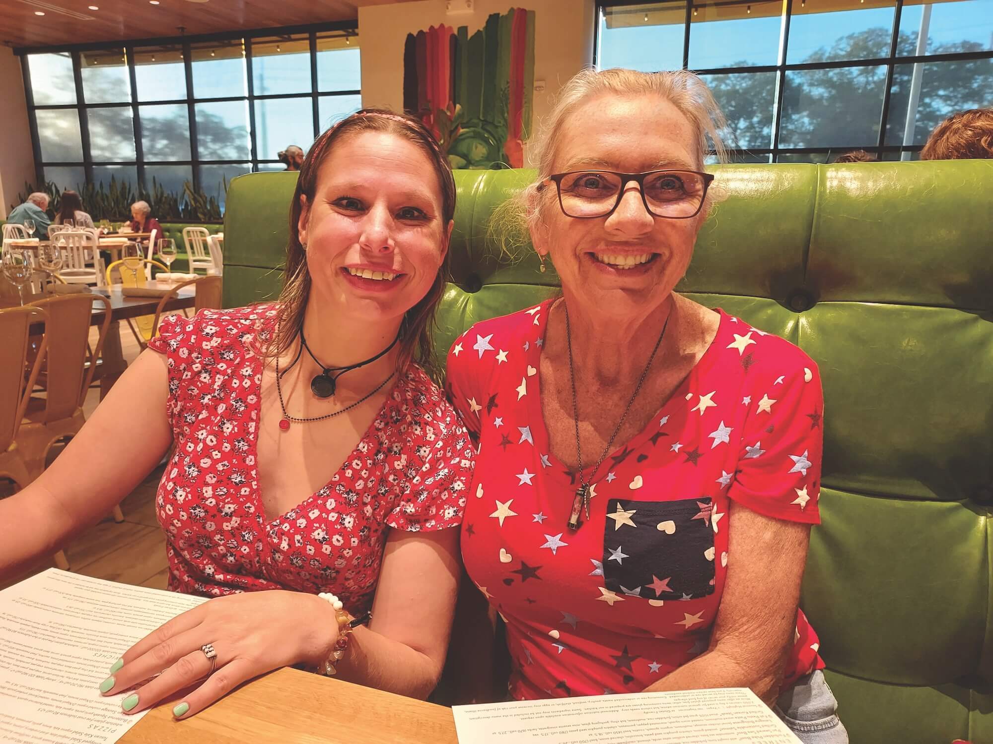 Wall Residences provider and individual sitting at a booth in a restaurant and smiling.