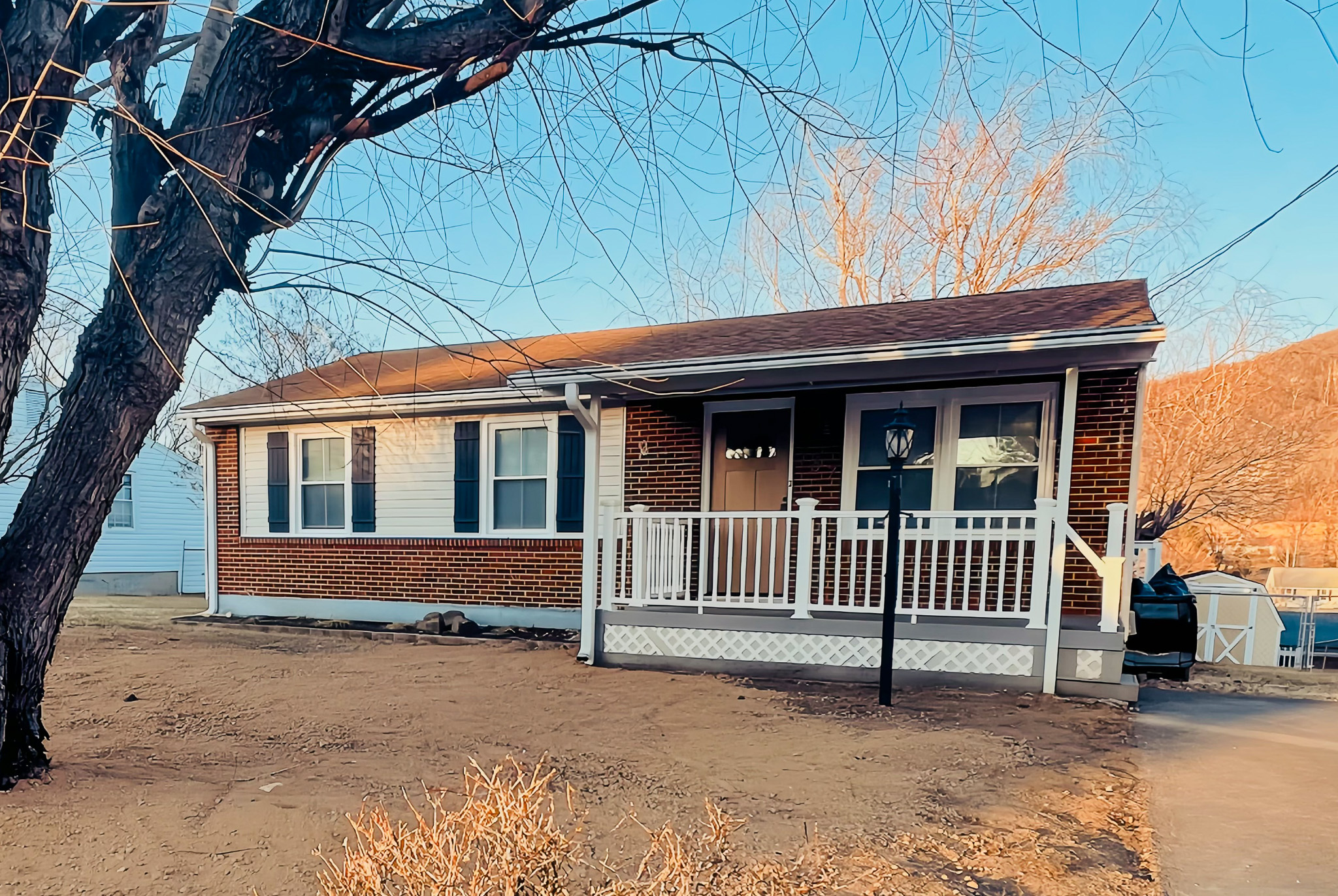 A small brick house with a white porch and leafless tree in the front yard belonging to sponsored residential provider Regina Hill in Roanoke, Virginia.