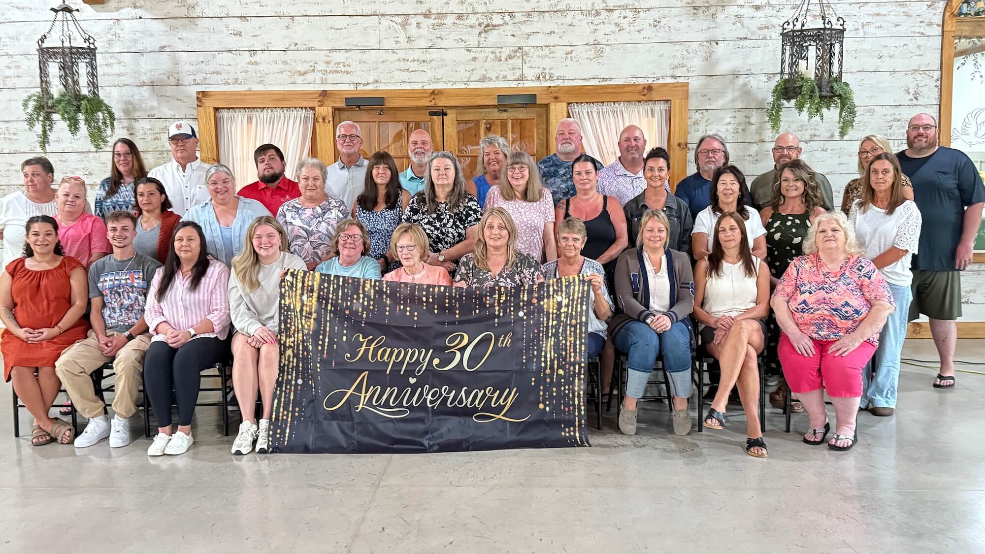 A group of providers close together holding a “Happy 30 Anniversary Banner” 