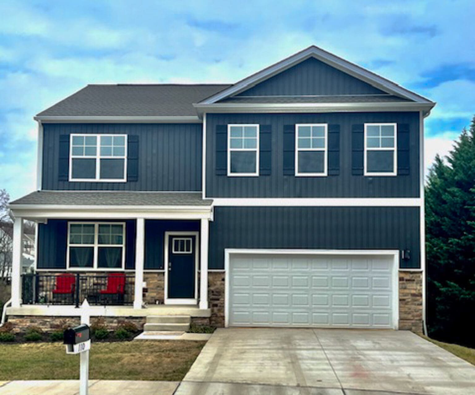 A two‑story modern house with dark siding, a large double garage, front porch with red chairs, and a wide concrete driveway belonging to Sponsored Residential Providers Shannon and Rebeka Knott in Staunton, Virginia.