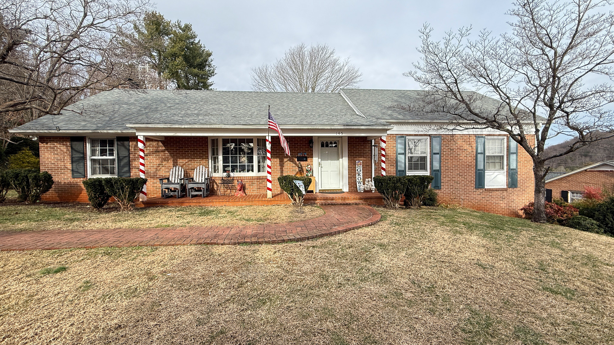 A brick single‑story house with a front porch, decorative columns, and a large yard stretching across the foreground belonging to Sponsored Residential Providers Angela and James Snyder in Rocky Mount, Virginia.
