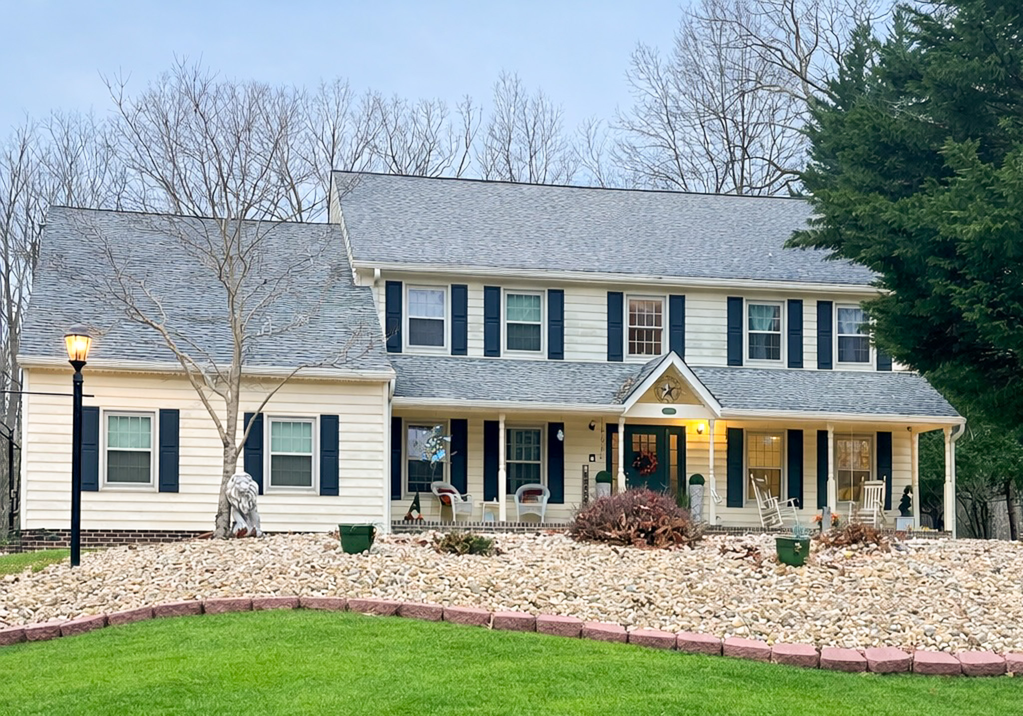 Front view of a two‑story house with beige siding, dark shutters, a covered porch, and landscaped rock beds in front lawn belonging to Sponsored Residential Provider Tarnisha Bradshaw in Fredericksburg, Virginia.