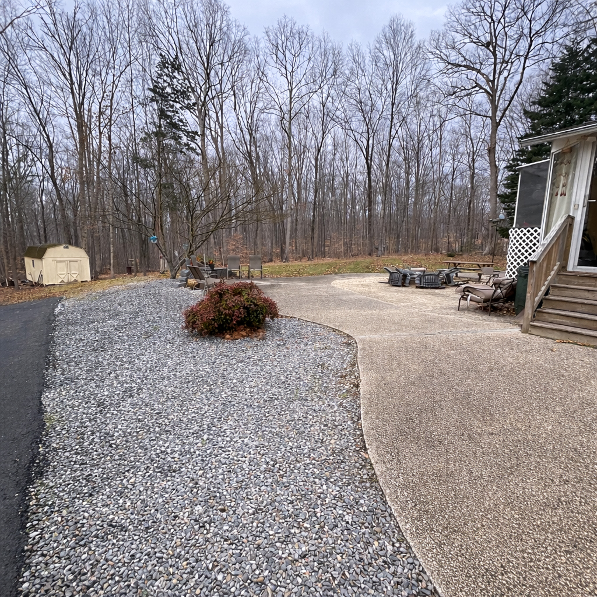 Outdoor area with a gravel path, concrete patio, seating area, and surrounding trees near a wooded yard at the home of  of Sponsored Residential Provider Tarnisha Bradshaw  in Fredericksburg, Virginia.