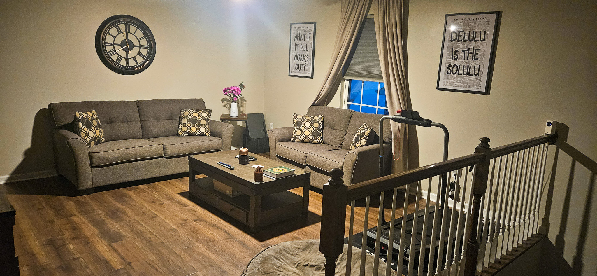 A warmly lit living room with two gray sofas, a wooden coffee table, and decorative wall art inside the home of Sponsored Residential Provider Vanessa Moore in Fredericksburg, Virginia.