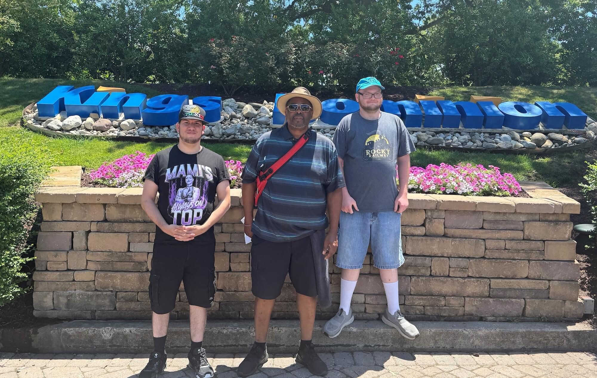 Three men standing in front of greenery at an amusement park