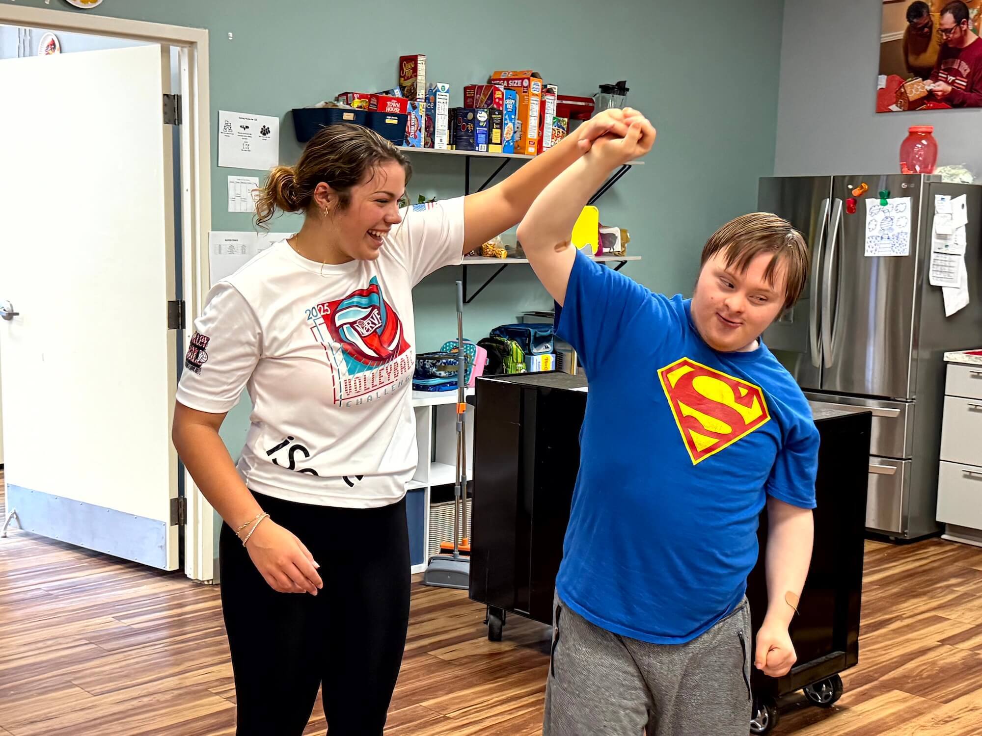 A female staff member twirls a young man as they dance at a Wall Star Center.