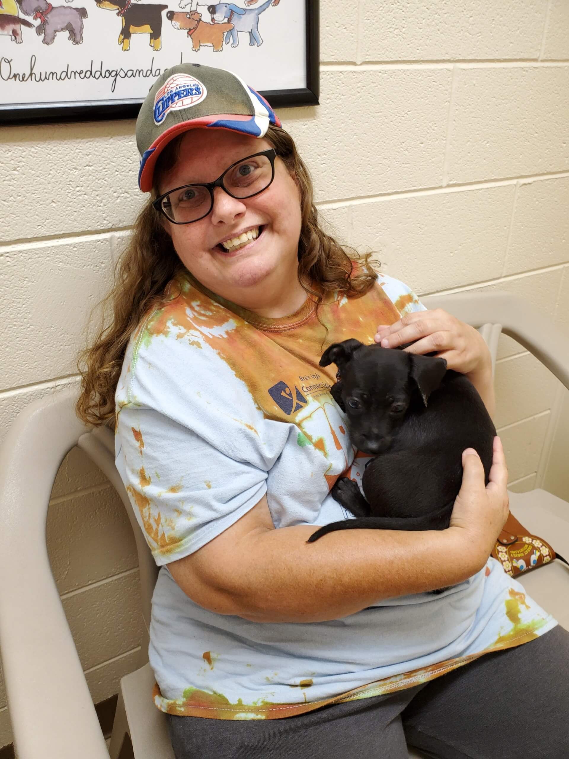 Smiling woman cuddles a small black puppy in her arms
