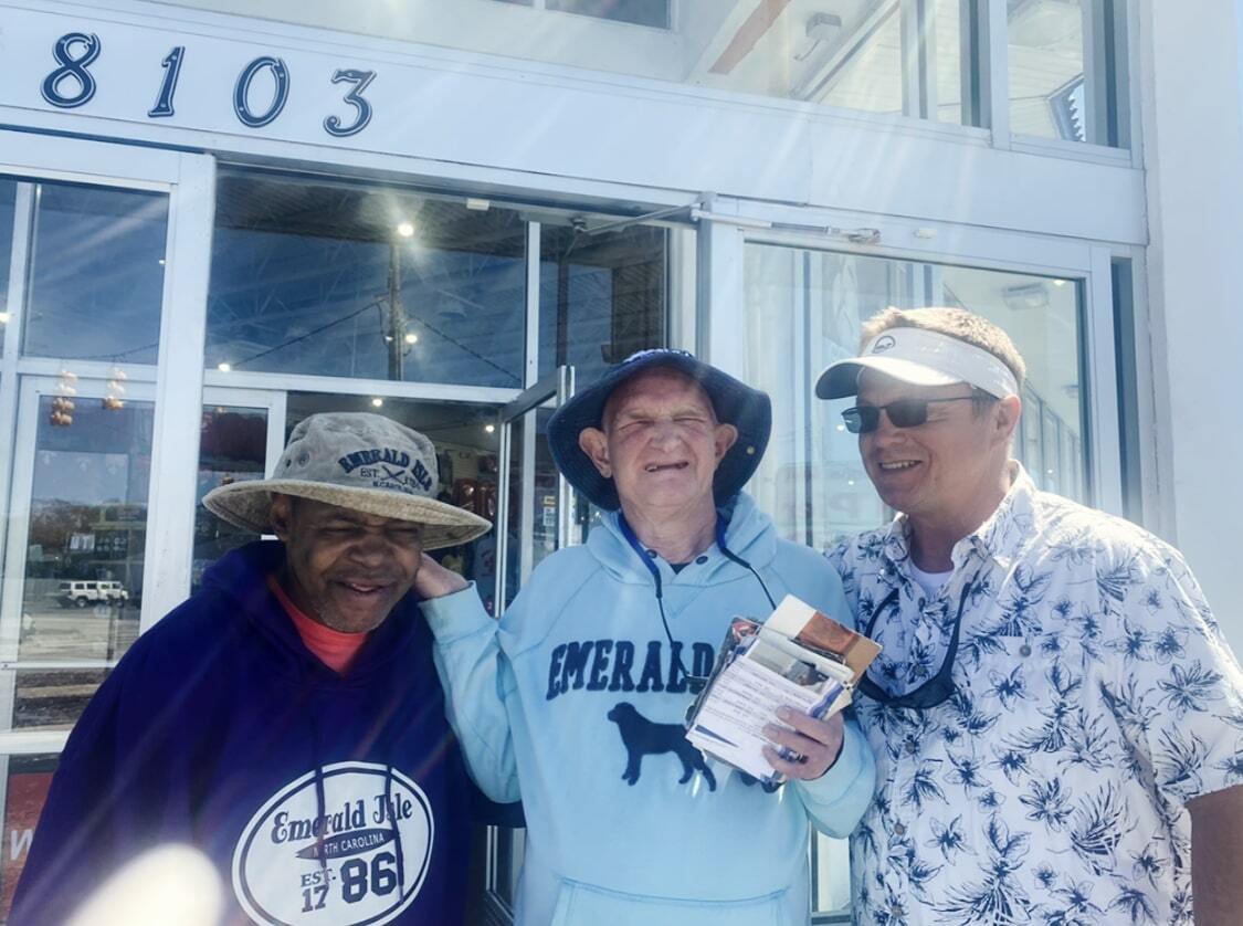 Three men smiling wearing hats outside