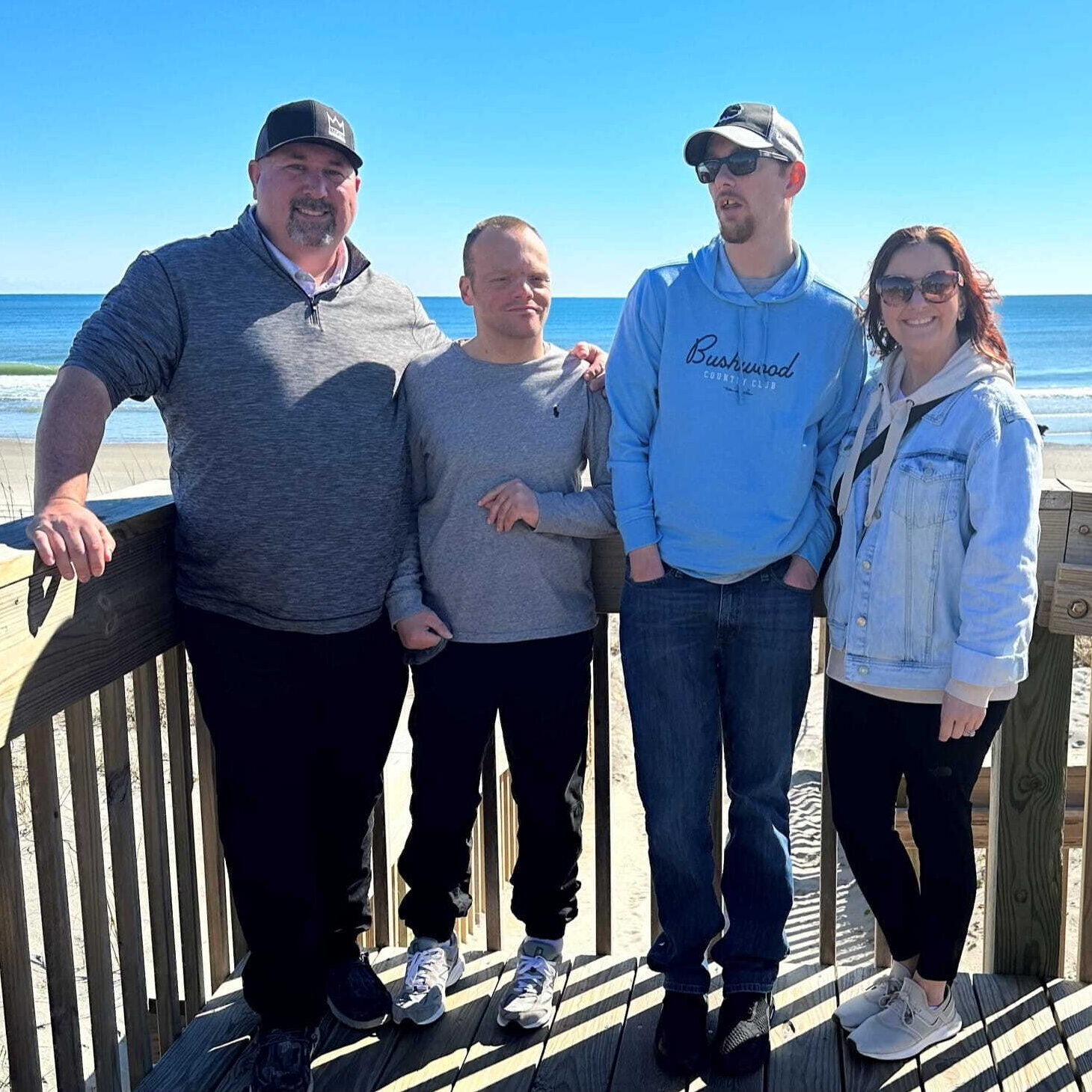 A group of people posing with the beach in the background.