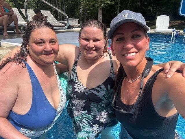 Three women standing in a swimming pool smiling in the camera