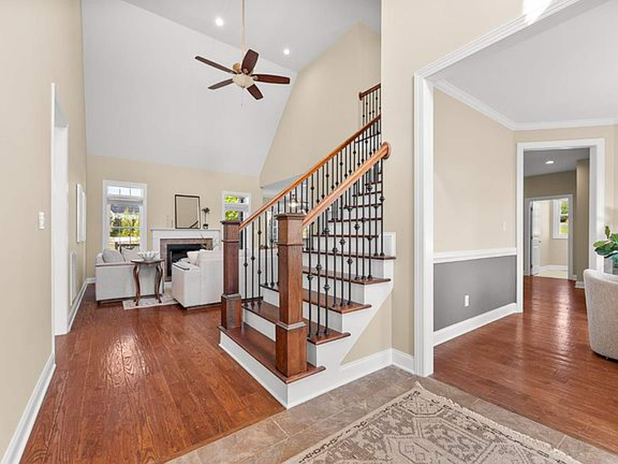 Bright interior view with hardwood floors, staircase with wood and iron railing, and a living room with a fireplace, in the home of sponsored residential provider Lisa Reed in Lynchburg, Virginia.