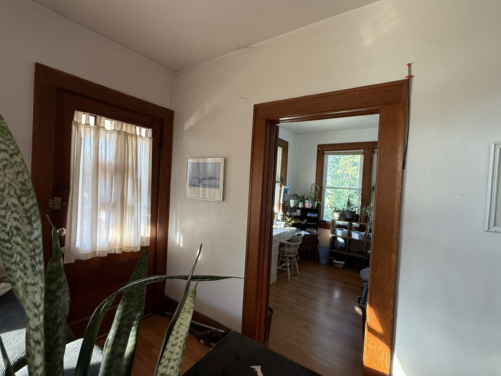 Hallway with wooden trim around doorways, showing a room beyond with a desk, chair, and large windows  inside the home of Sponsored Residential Provider Tammy Hunt in Floyd, Virginia.