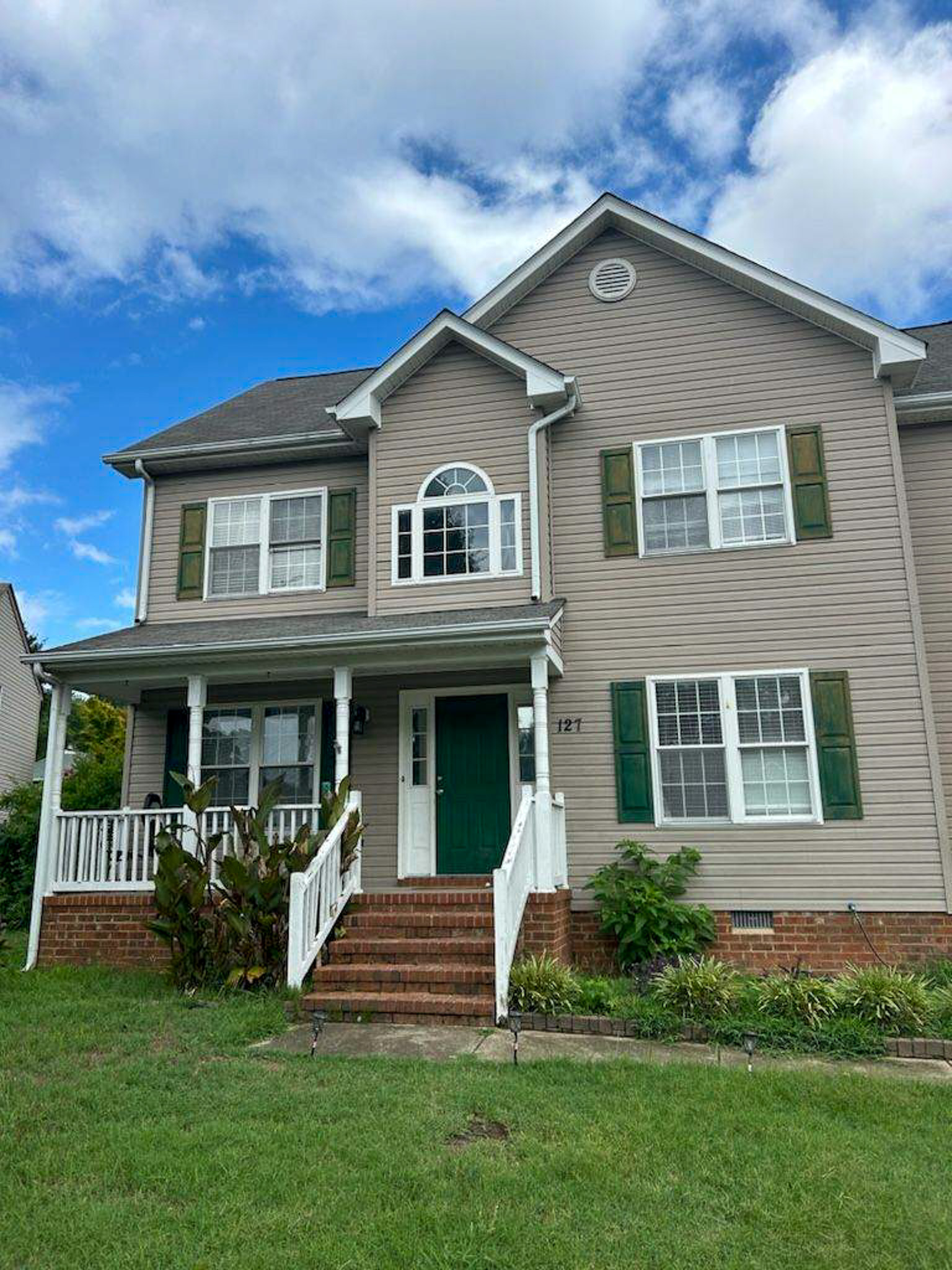 Two‑story house with beige siding, green shutters, and a front porch with white railings, viewed from the lawn belonging to Sponsored Residential Provider Camille Swift in Hampton, Virginia.