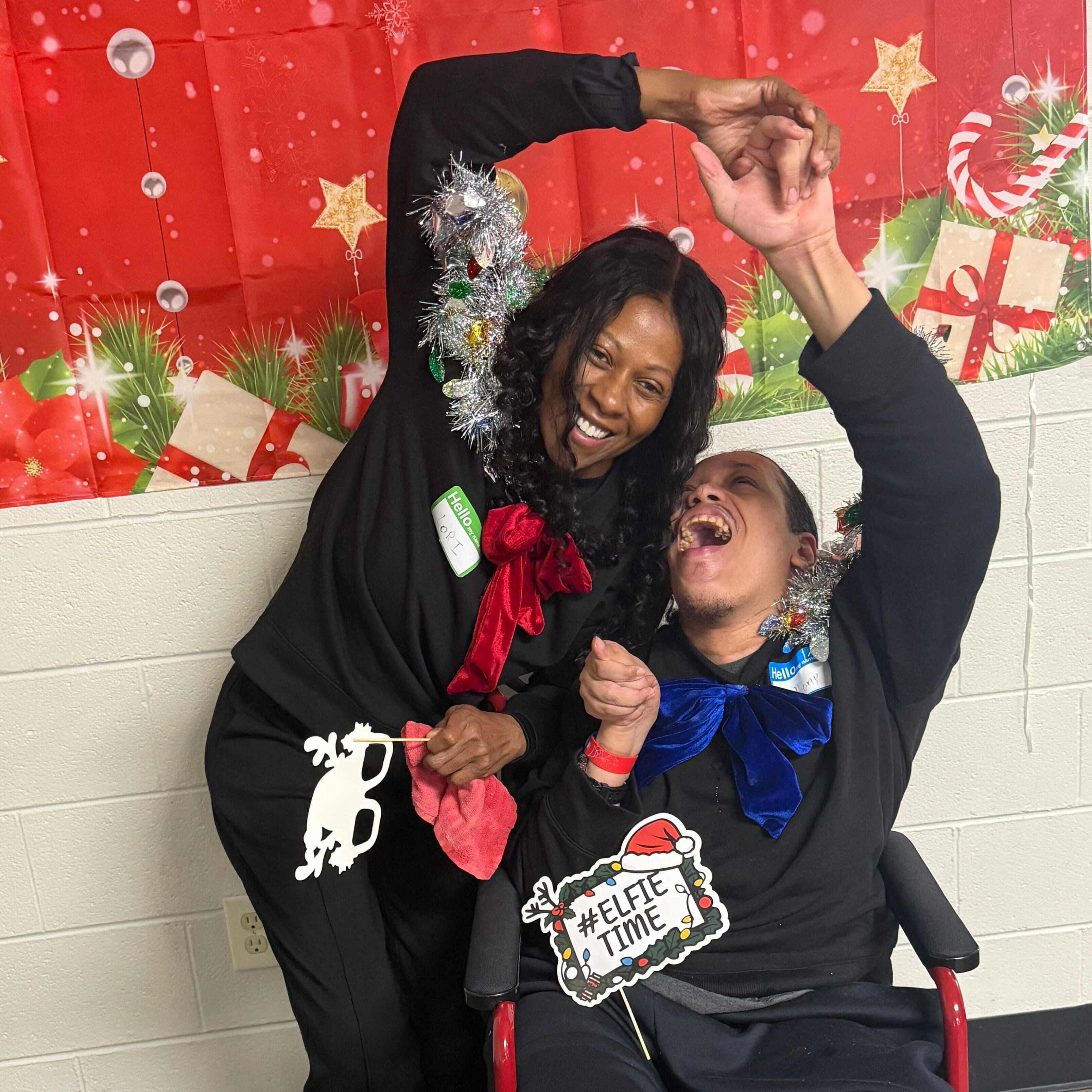 A woman and a man in wheelchair using photo booth props at a Christmas party