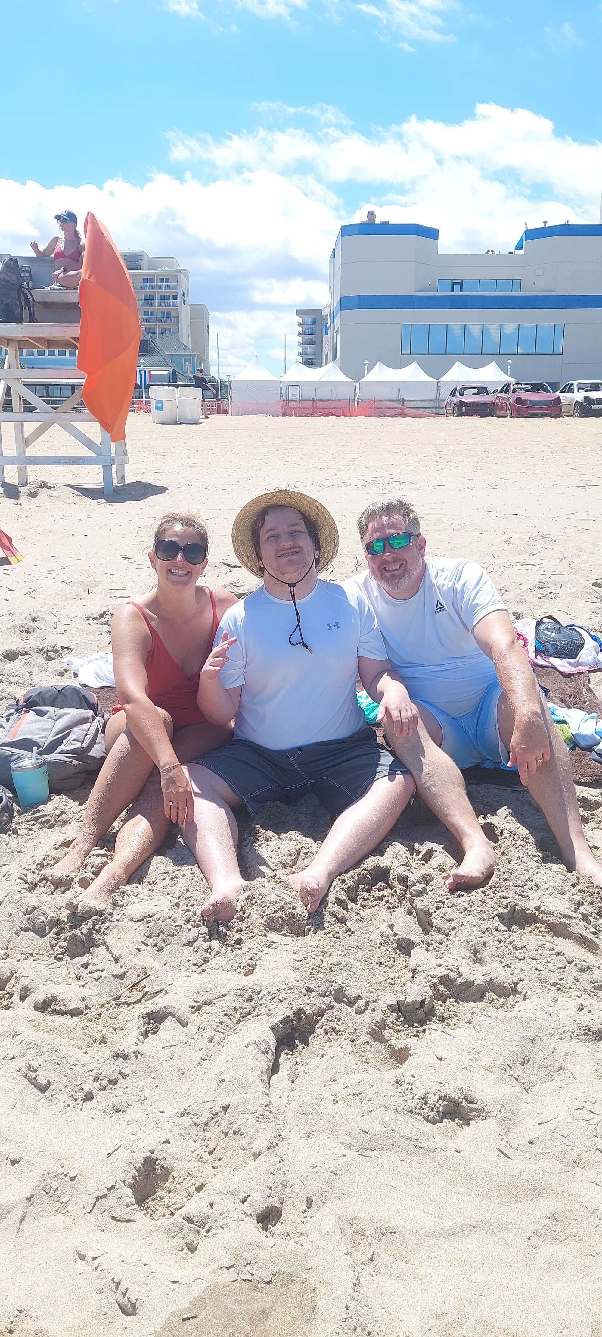 Two men and a woman sitting on the sand at the beach