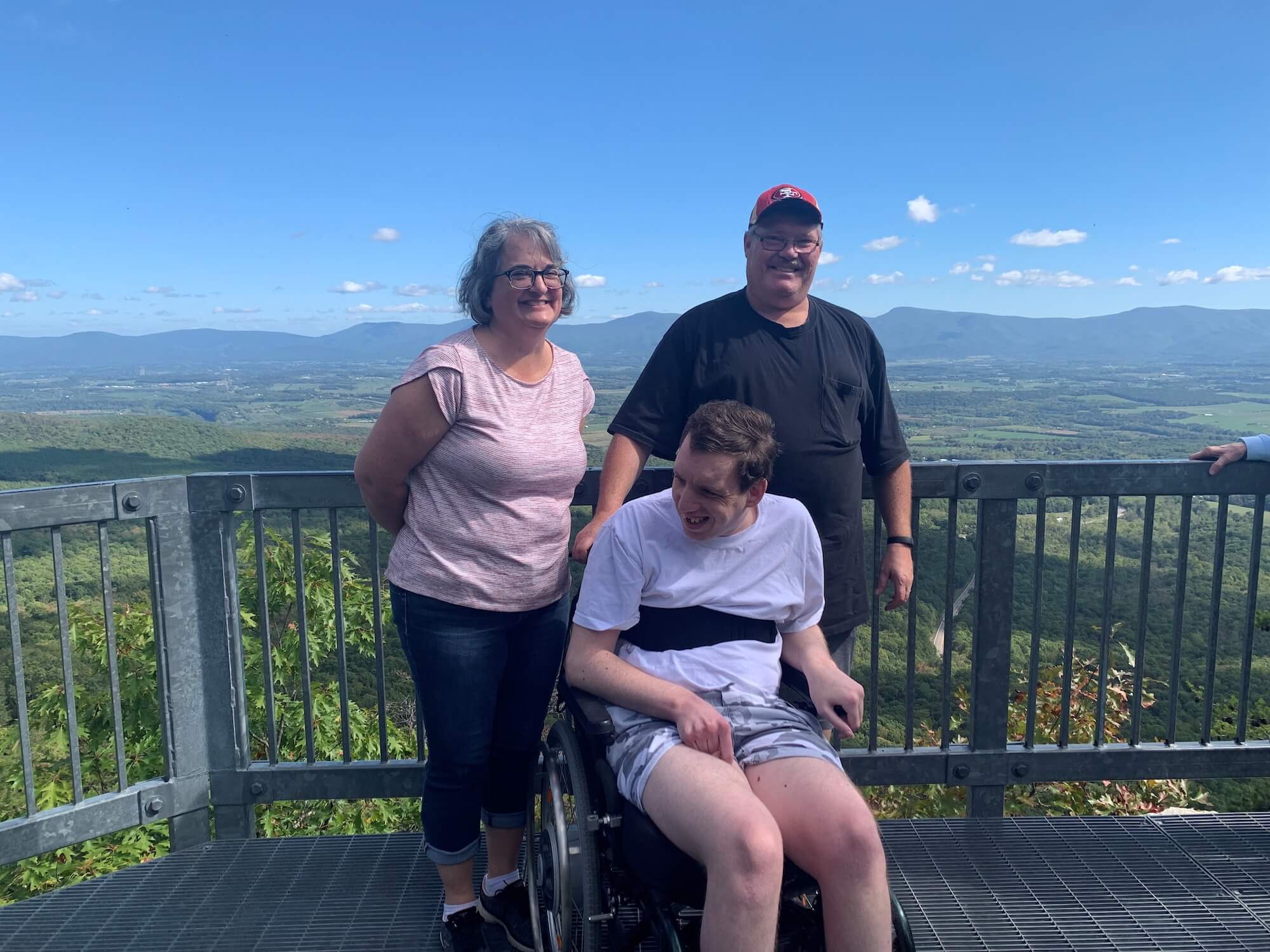 Two men and a woman at a scenic overlook smiling at the camera