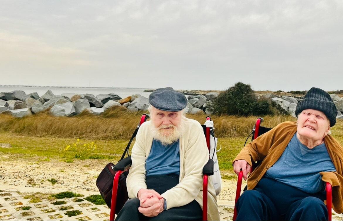 Two twin men sitting in wheelchairs outside at the beach